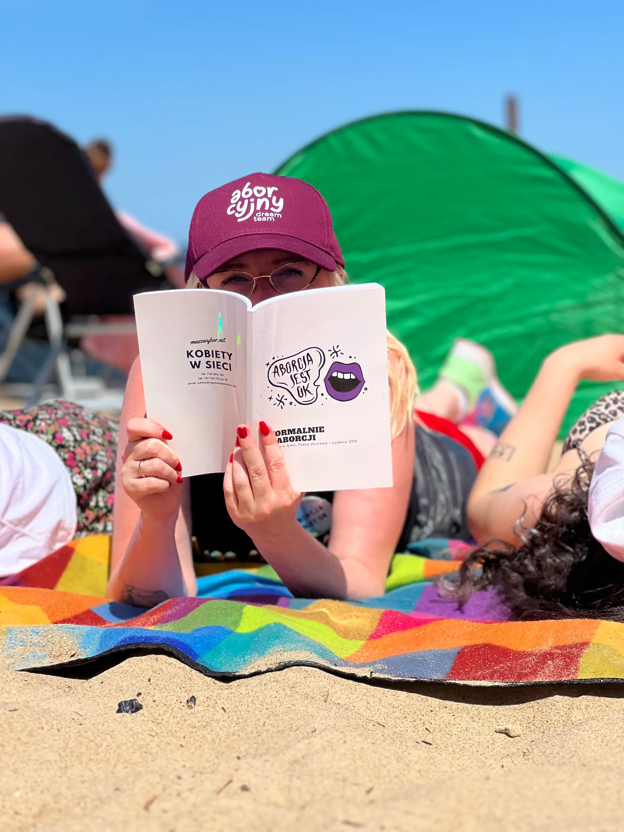 Kobieta czyta o aborcji leżąc na plaży.